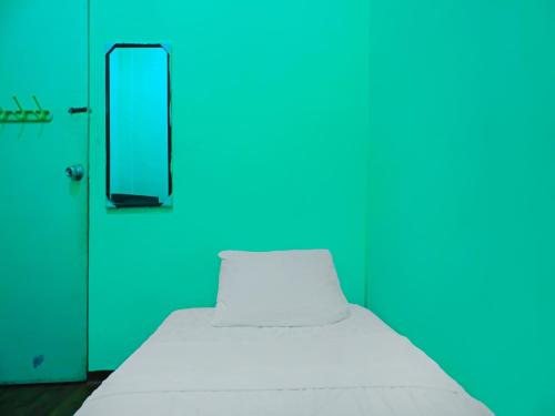 a white bed in a room with a blue door at SPOT ON 92186 Penginapan Lorra in Nagoya