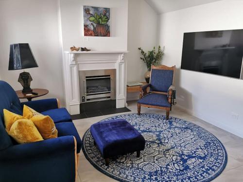 a living room with blue chairs and a fireplace at The Shoemaker's Cottage in Richmond