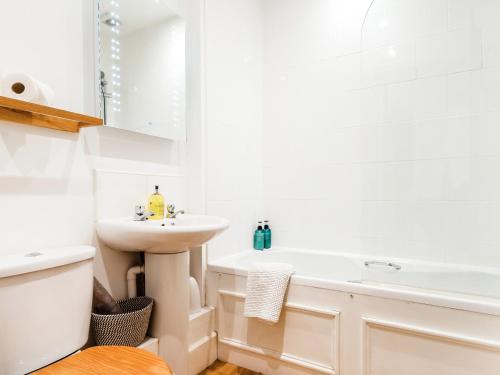 a white bathroom with a sink and a bath tub at Riding Cottage - Uk37449 in Pateley Bridge