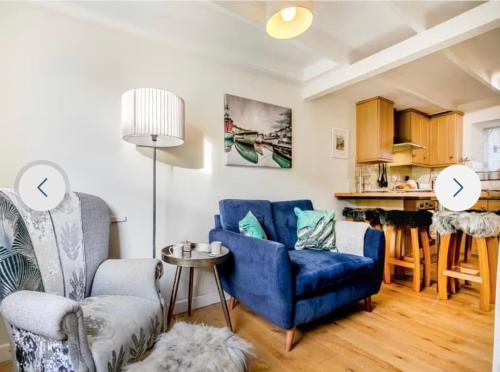 a living room with two blue chairs and a table at Fulmar Cottage in Mevagissey