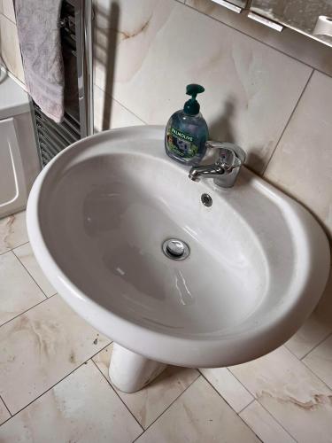 a white sink with a bottle of soap on it at Luton Town House Near AIRPORT in Luton