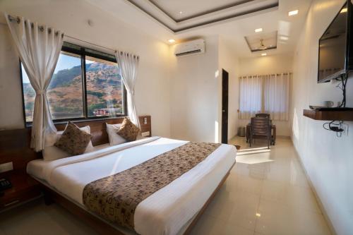 a bedroom with a large bed with a large window at Hotel Jagadguru Lonavala in Lonavala