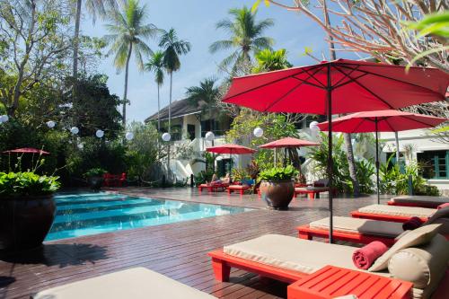 einen Pool mit Stühlen und Sonnenschirmen neben einem Resort in der Unterkunft Villa Maly Boutique Hotel in Luang Prabang