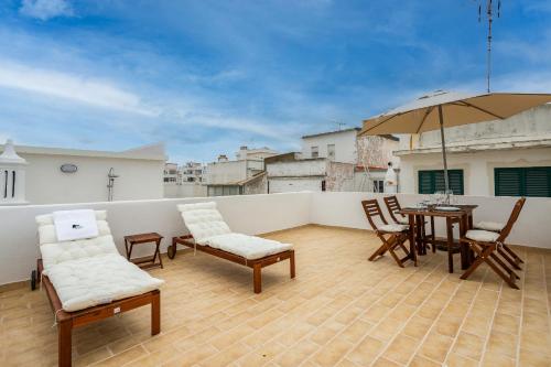 a balcony with a table and chairs and an umbrella at Tia Anica House II - apartment with terrace in central Fuseta beach village in Fuzeta