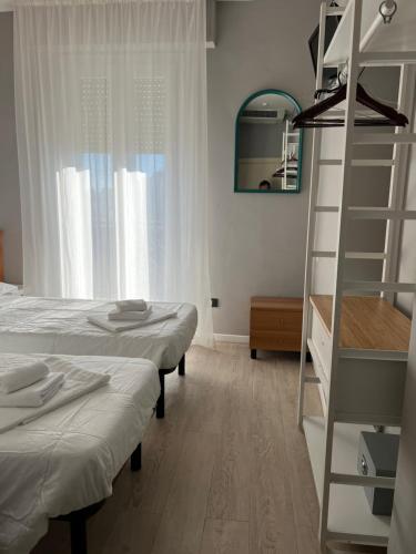 a bedroom with two beds and a ladder and a mirror at Hotel Stella D'Italia in Rimini
