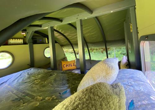Un oso de peluche sentado en una cama en un autobús. en Exclusive Use Riverside Landpods at Wildish Cornwall, en Bodmin