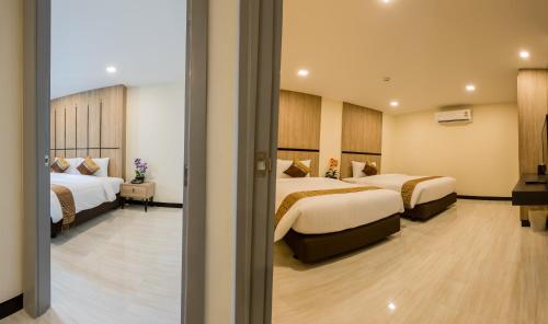 a hotel room with two beds and a window at Crystal Palace Luxury Hotel Pattaya in North Pattaya