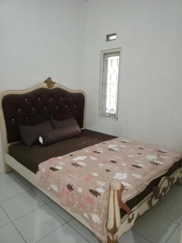 a bedroom with a bed with a floral bedspread and a window at Mutiara Dieng in Wonosobo