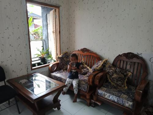 a little boy sitting on a couch taking a picture at Mutiara Dieng in Wonosobo