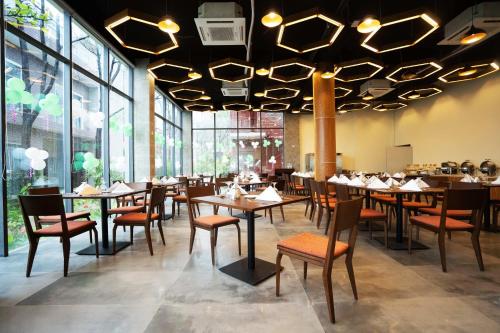 a dining room with tables and chairs and large windows at DERA Resort & Spa in Cox's Bazar