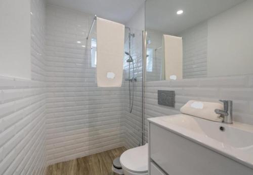 La salle de bains blanche est pourvue d'un lavabo et de toilettes. dans l'établissement Tia Anica House II - apartment with terrace in central Fuseta beach village, à Fuzeta