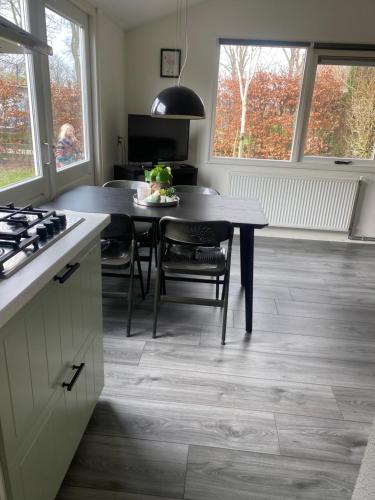 a kitchen with a table and a dining room with a stove at Chalet Bergen NH, Schoorl, Schoorldam in Warmenhuizen