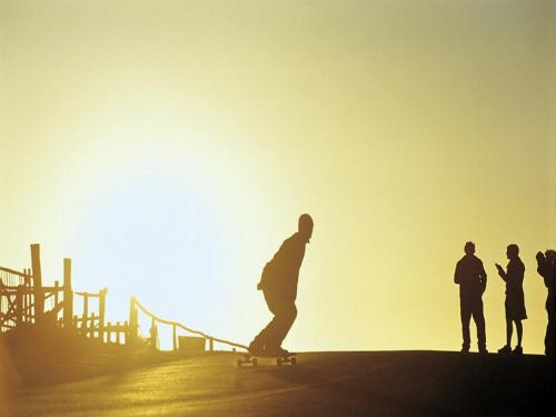 a man riding a skateboard down a hill with others at Cuarzo Lodge in Pichilemu