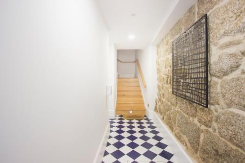 a hallway with a stone wall and a checkered floor at Santa Luzia Apartments By Guestify in Guimarães