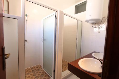 La salle de bains est pourvue d'une cabine de douche en verre et d'un lavabo. dans l'établissement La Maison Jaune Dakhla Maison d'hôtes, à Dakhla