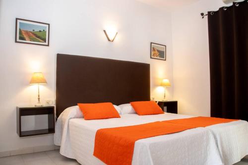 1 dormitorio con 1 cama grande y 2 almohadas de color naranja en Hostal El Capi en Zahora