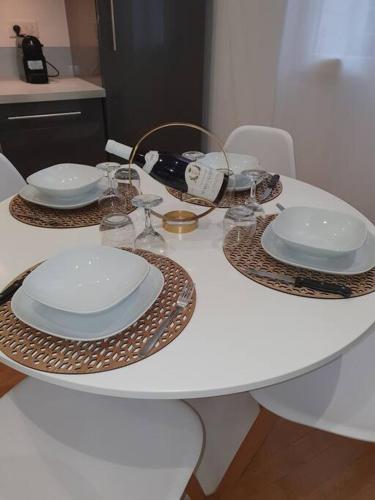 a white table with plates and wine glasses on it at L'APPART'JEANNIN HYPER CENTRE in Dijon