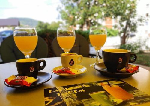 uma mesa com dois copos de sumo de laranja e chávenas de café em Planinska kuća za odmor Vuković em Podgrab