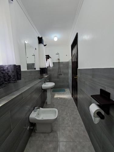a bathroom with a toilet and a bidet and a sink at Enaiteru in Oyugis