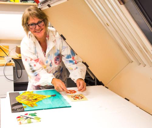 a woman standing at a table making a painting at Lensmannsgården in Namdalseid