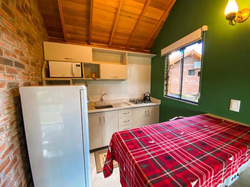 a kitchen with green walls and a red plaid table cloth at Vovô Emílio Chalés in Nova Petrópolis