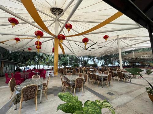 Un restaurante al aire libre con mesas, sillas y sombrillas. en Gold Coast Morib International Resort Studio Room, en Banting