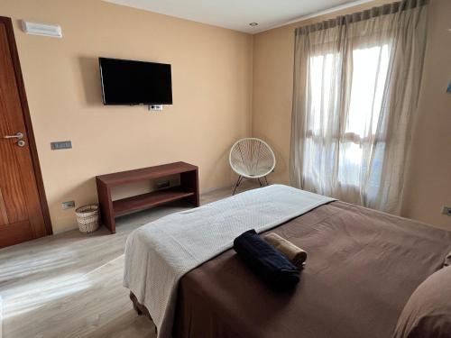 a bedroom with a bed and a flat screen tv at Orietta Residencial in Mindelo