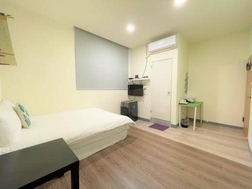 a bedroom with a white bed and a door at Fengjia 08 home in Taichung