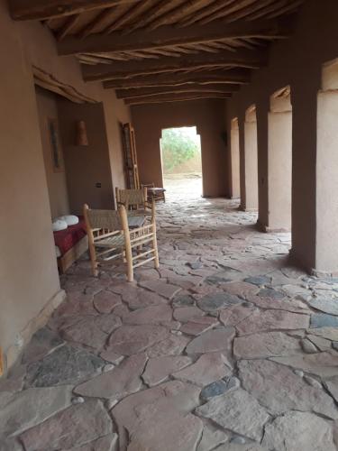 a stone hallway with two chairs in a building at Dar Paru in Mhamid