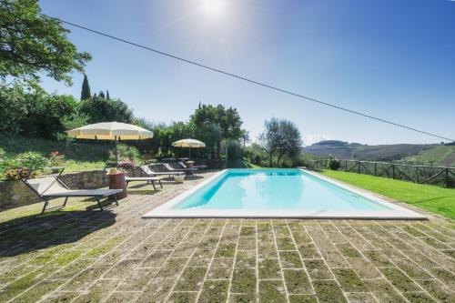 a swimming pool with two chairs and an umbrella at Agriturismo La Casellina in Monticchiello