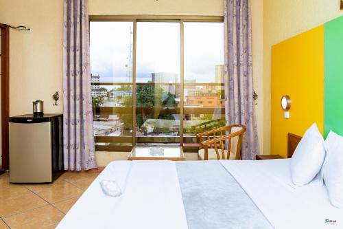 a hotel room with a bed and a large window at Séréna Hôtel in Douala