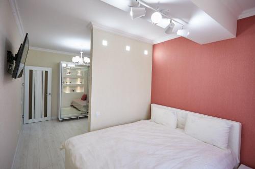 a bedroom with a white bed and a red wall at 1BR ultracentral Chișinău in Chişinău