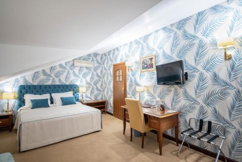 een slaapkamer met een bed, een bureau en een televisie bij Swiss Hotel in Lviv
