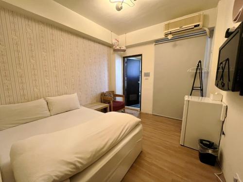 ein Schlafzimmer mit einem weißen Bett in einem Zimmer in der Unterkunft FengChia FUN House in Taichung