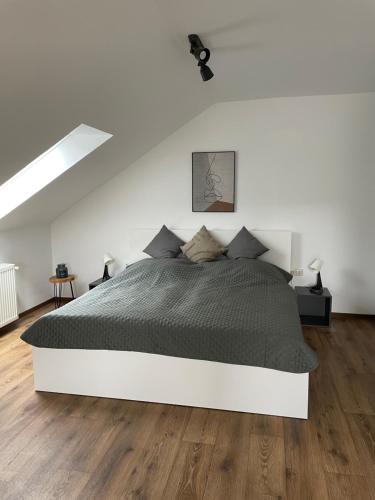 a white bedroom with a large bed and wooden floors at Ferienwohnung Ela in Bad Kissingen