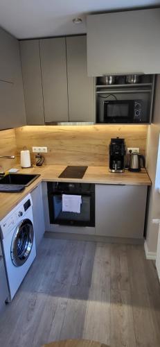 a kitchen with a stove and a washing machine at Modern studio apartment near the beach - 5 min walk in Liepāja