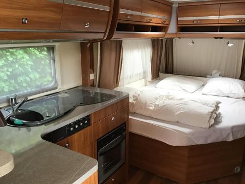 uma pequena cozinha com uma cama e um lavatório num trailer em Gezellige luxe caravan met zwembad in zuid- Bourgogne em Anglure-sous-Dun