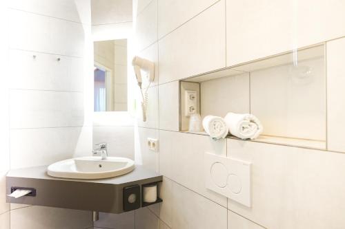 a white bathroom with a sink and a mirror at Hotel Kannenkeller in Lauingen