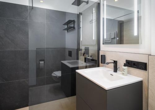 a bathroom with a sink and a toilet and a mirror at Auhof - Apartments Bad Gastein in Bad Gastein