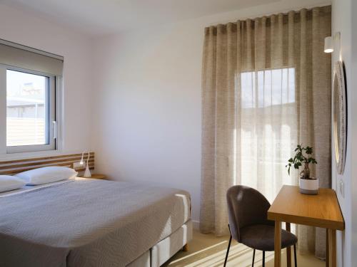 a bedroom with a bed and a desk and a window at Sea La Vie in Adelianos Kampos