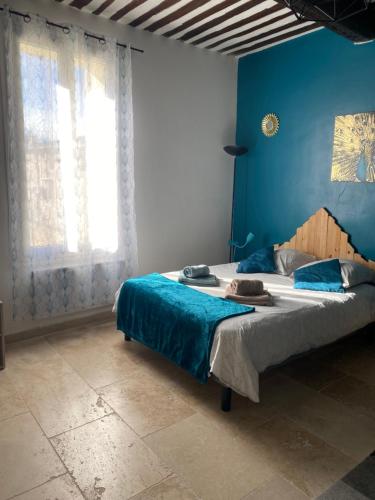 une chambre avec un grand lit avec un mur bleu dans l'établissement Studio de charme le Clos de l'Etang + place de parking, à LʼIsle-sur-la-Sorgue