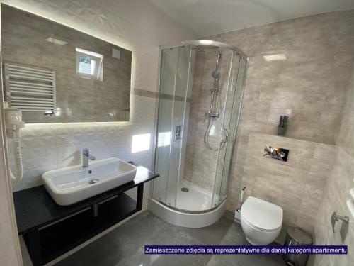 a bathroom with a shower and a sink and a toilet at Apartamenty Wakacyjna Wioska Ngô 20m od Suntago in Mszczonów