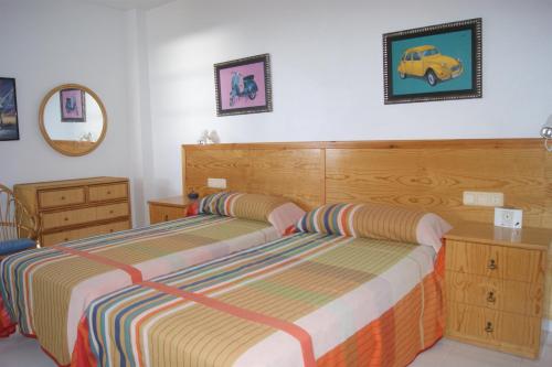 a bedroom with two beds and a wooden headboard at Las Haciendas Marineu in Alcossebre