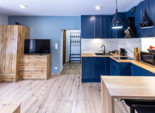 uma cozinha com armários azuis e pisos em madeira em Apartament Sarenka em Szklarska Poręba