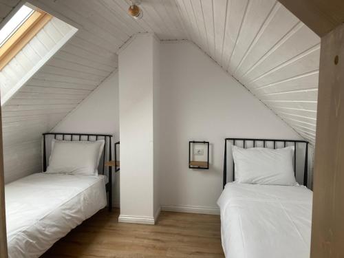 2 camas num quarto no sótão com paredes brancas em Cabana Maia em Fundstica