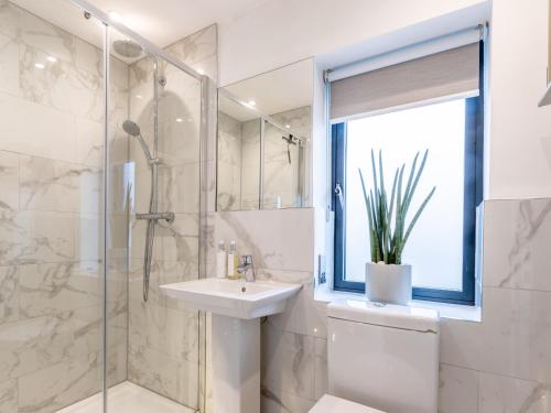 a white bathroom with a sink and a shower at 5 Clough Cottages in Clitheroe