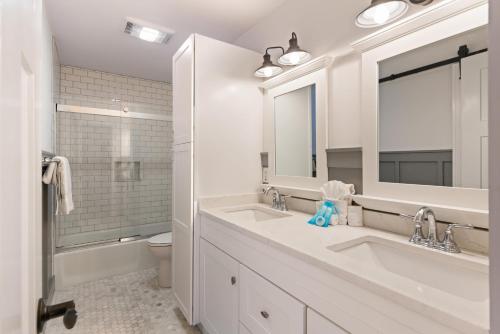 ein weißes Badezimmer mit zwei Waschbecken und einem Spiegel in der Unterkunft Sea Side Cottage - 4217 Second Street in East End