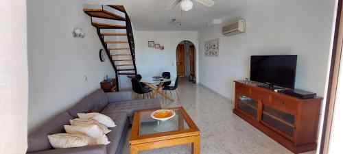 ein Wohnzimmer mit einem Sofa und einem TV in der Unterkunft Casita del Sol - duplex with Sea View and community Pool on the Cumbre del Sol in Benitatxell