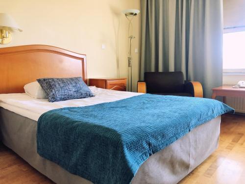 una camera da letto con un letto con una coperta blu sopra di Hotel Kurikka a Kurikka