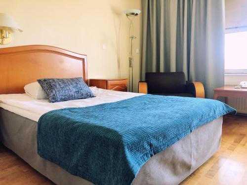 a bedroom with a bed with a blue blanket on it at Hotel Kurikka in Kurikka